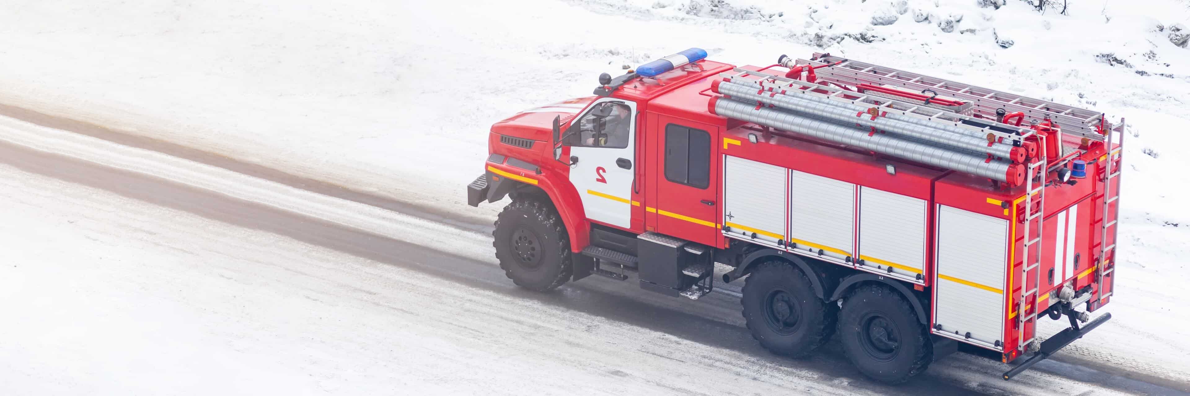 红色消防车在积雪道路上行驶，适应车队管理中的独特预算与现场限制